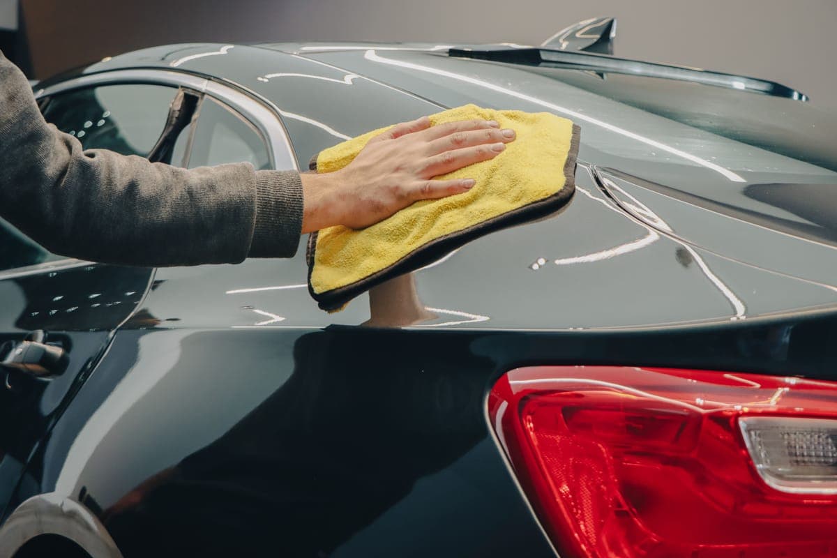 A clay bar and spray lubricant resting on a smooth light-colored car panel