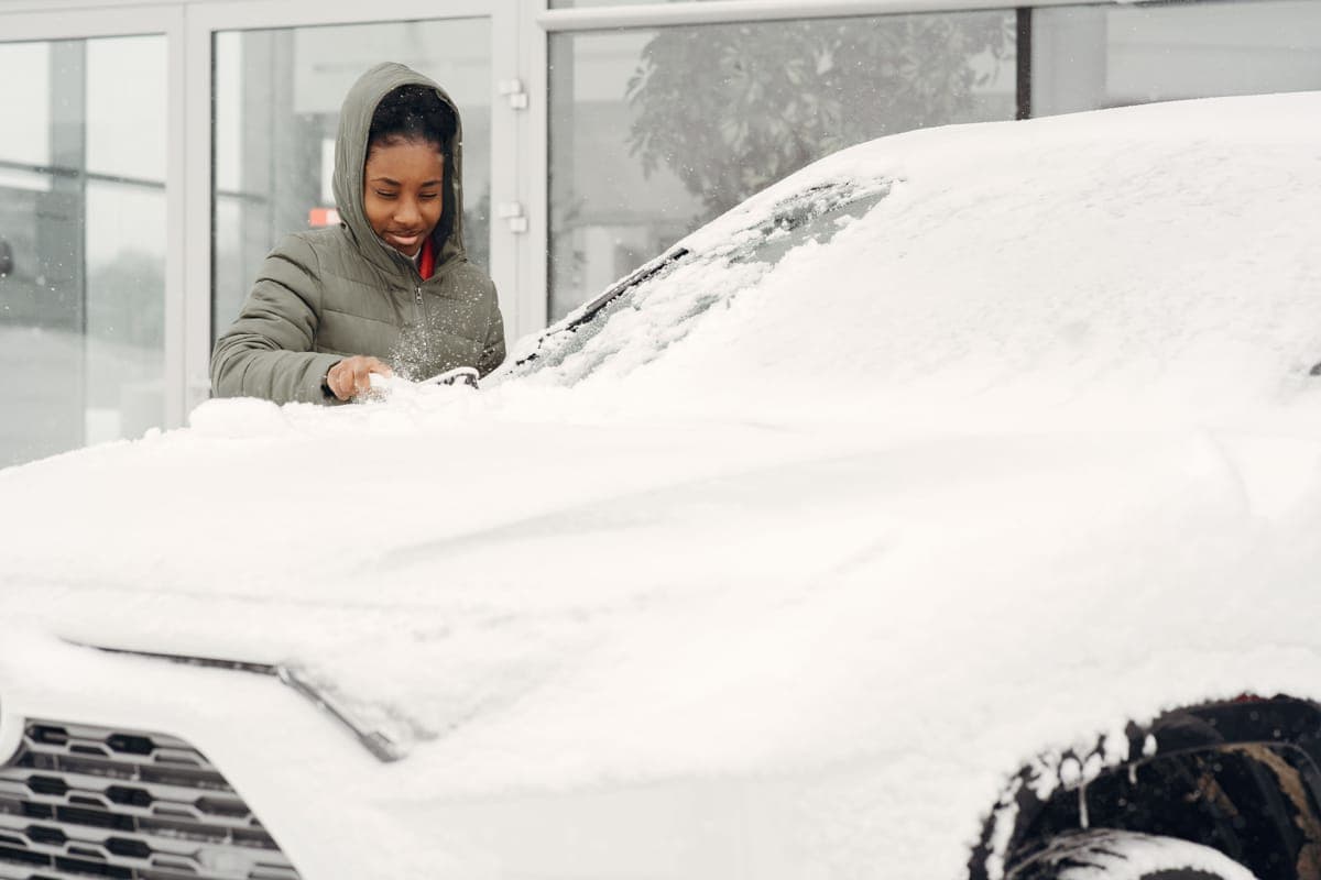 A foam cannon attached to a pressure washer lance covering a car in white foam