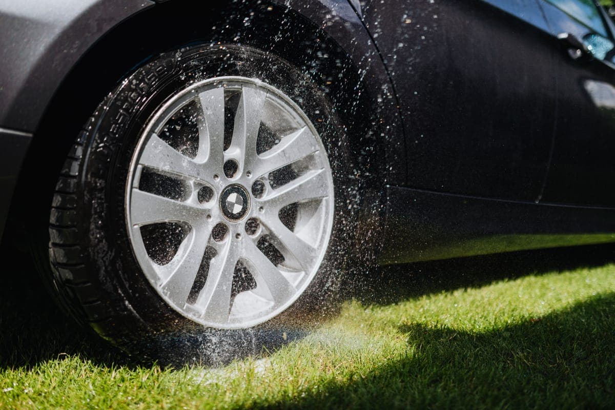 Purple iron remover reacting on a car wheel and lower panel in daylight