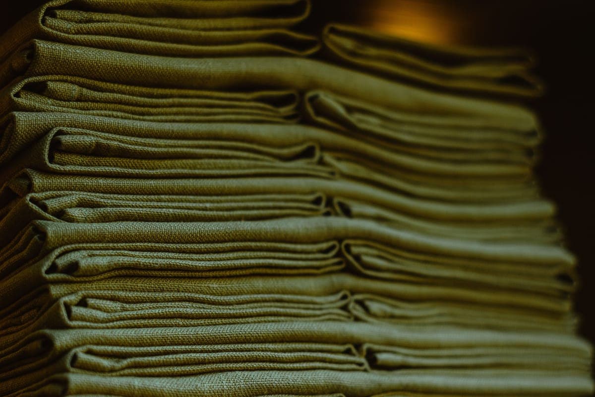 A neat stack of folded microfiber towels in several colors on a bright bench