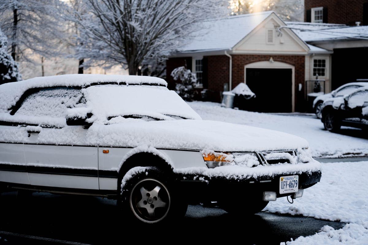 Thick snow foam covering the front of a light-colored car on a driveway