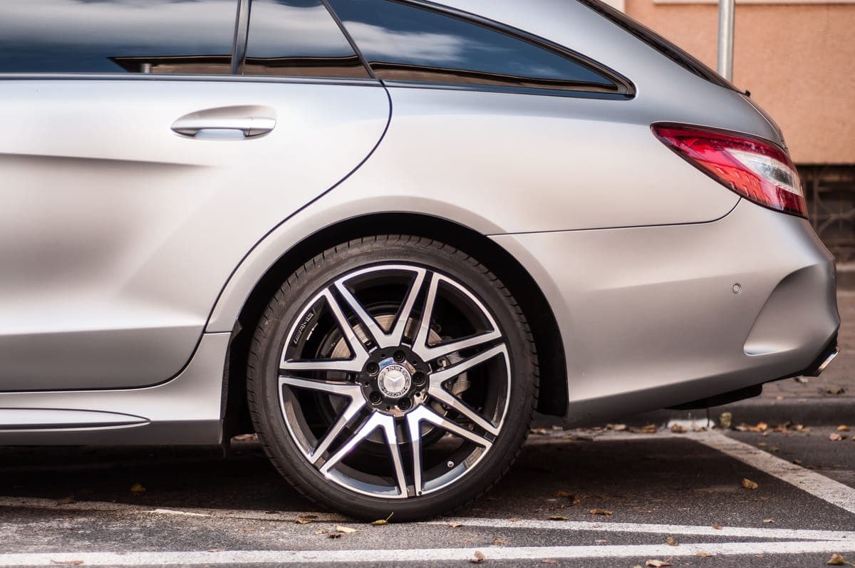 Wheel cleaner foaming on an alloy wheel with a soft brush resting against the tire